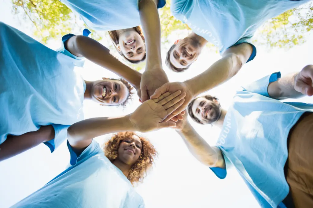 a group of workers put their hands together in a circle.