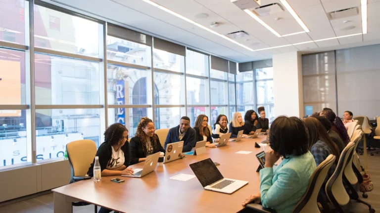 group of people sitting beside rectangular wooden table with laptops