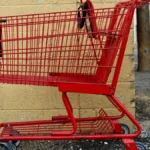 Empty red shopping cart against a yellow wall, illustrating Shopify abandoned cart recovery