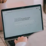 Person typing into a chat assistant on a laptop, illustrating Shopify AI tools