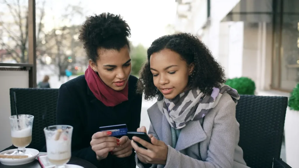 Two shoppers paying on a phone with a credit card, illustrating Shopify conversion rate optimization