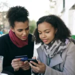 Two shoppers paying on a phone with a credit card, illustrating Shopify conversion rate optimization