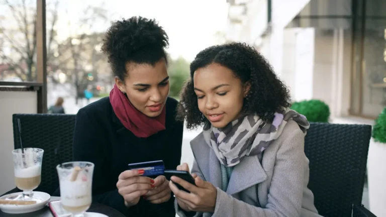 Two shoppers paying on a phone with a credit card, illustrating Shopify conversion rate optimization