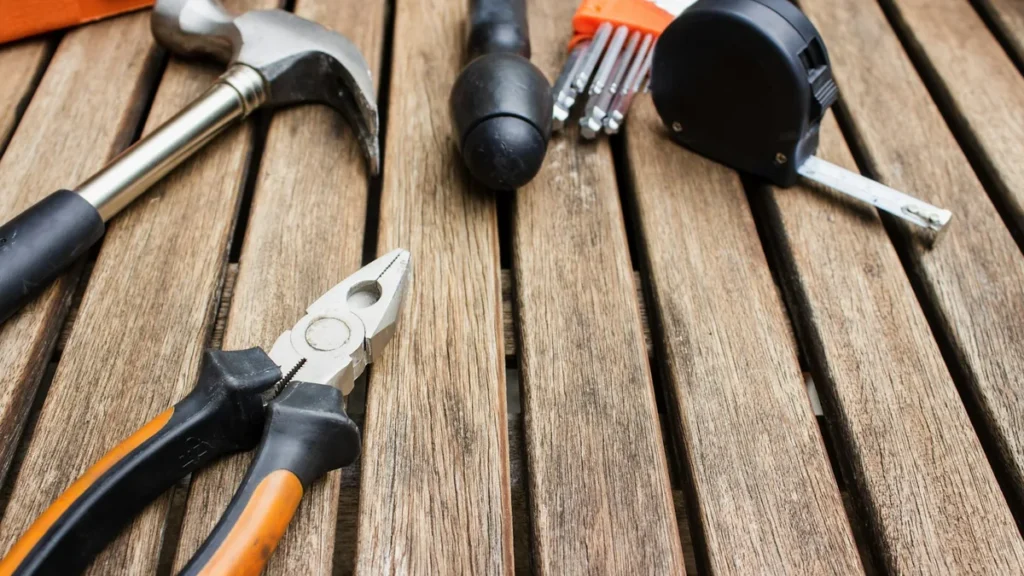 Hammer, pliers and tape measure on a wooden table, illustrating a Shopify store maintenance checklist