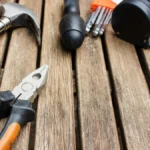 Hammer, pliers and tape measure on a wooden table, illustrating a Shopify store maintenance checklist