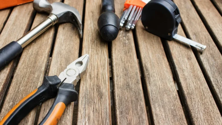 Hammer, pliers and tape measure on a wooden table, illustrating a Shopify store maintenance checklist