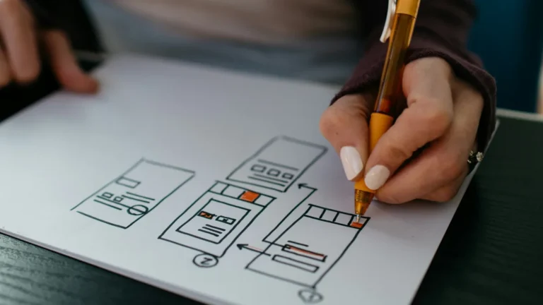 Hand sketching website wireframes on paper, illustrating a Shopify store redesign